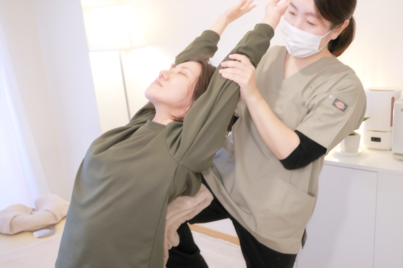 施術者が胸まわりを開くストレッチを行い、お客様が気持ちよさそうに伸びをしている様子