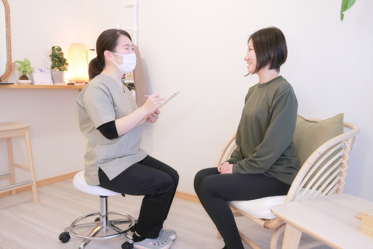 施術者とお客様が向かい合って座り、笑顔でカウンセリングをしている様子