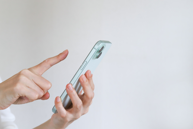 スマートフォンを操作して予約をする女性の手元